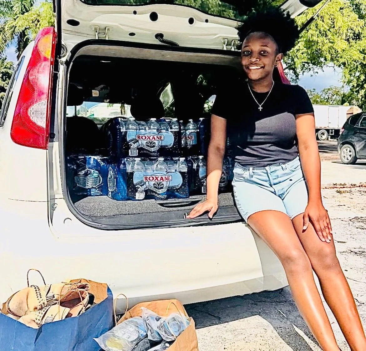 A volunteer beside a vehicle loaded with cases of bottled water at the Donation Hub.